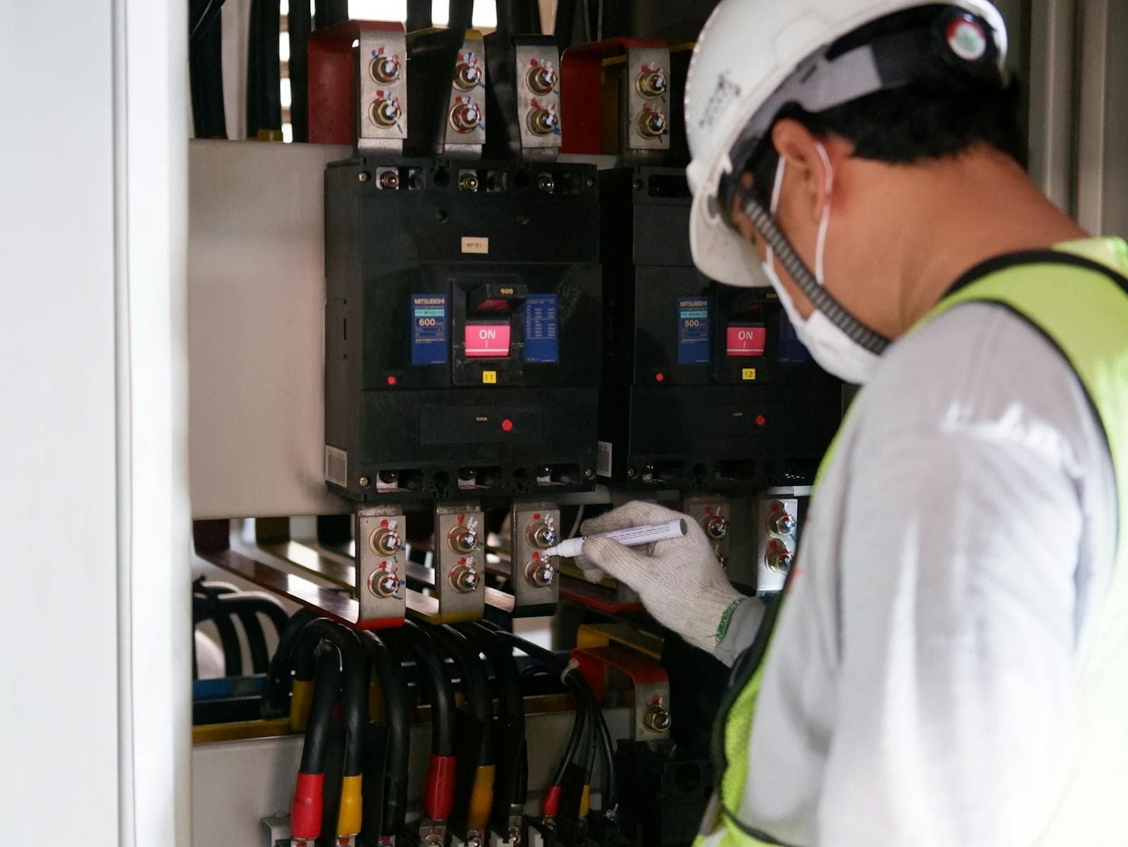 Technician inspecting a commercial electrical switchboard with moulded-case circuit breakers