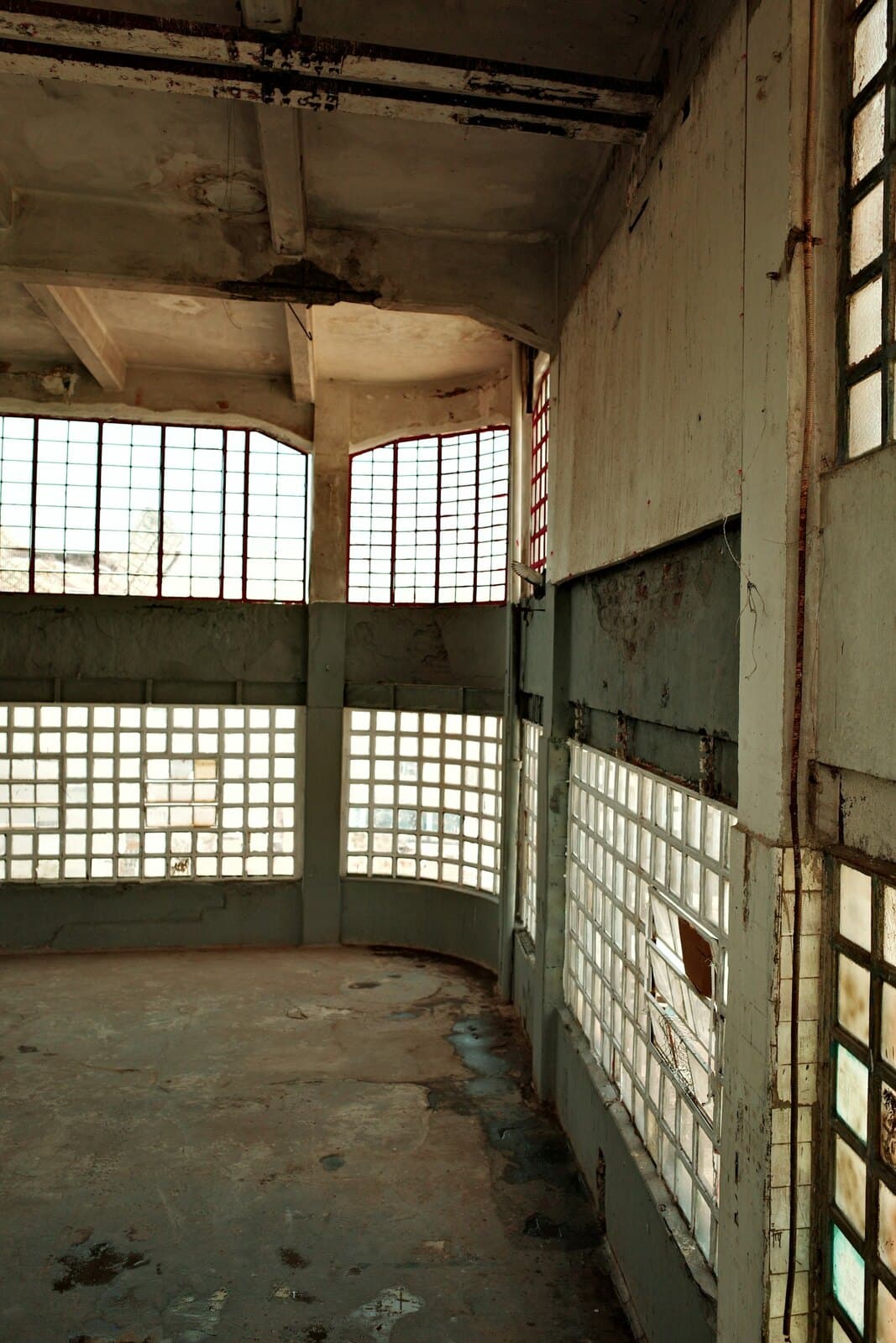 Weathered, empty industrial interior with light through aged windows, entropy at work in a building