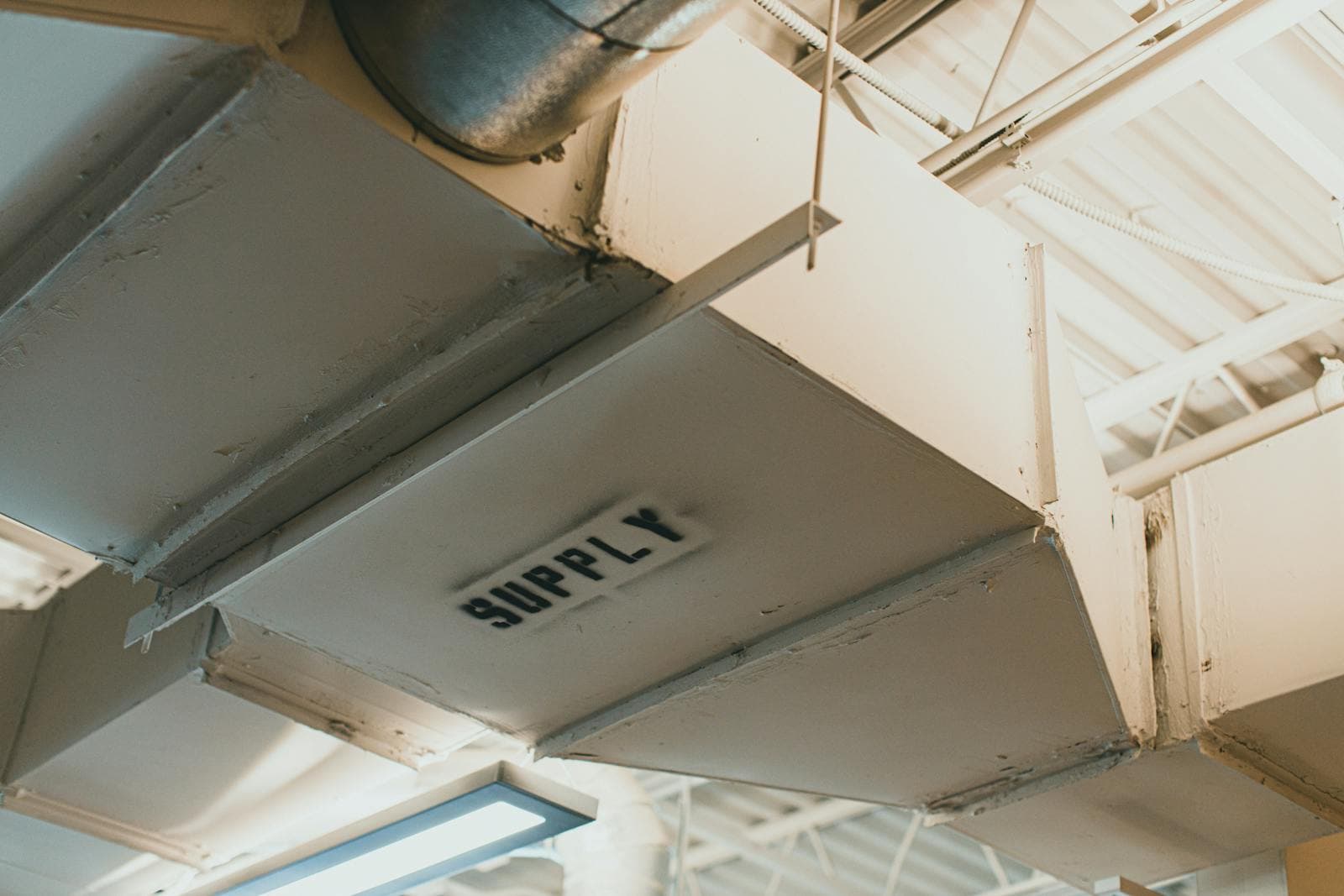 White HVAC supply air ductwork below a building roof