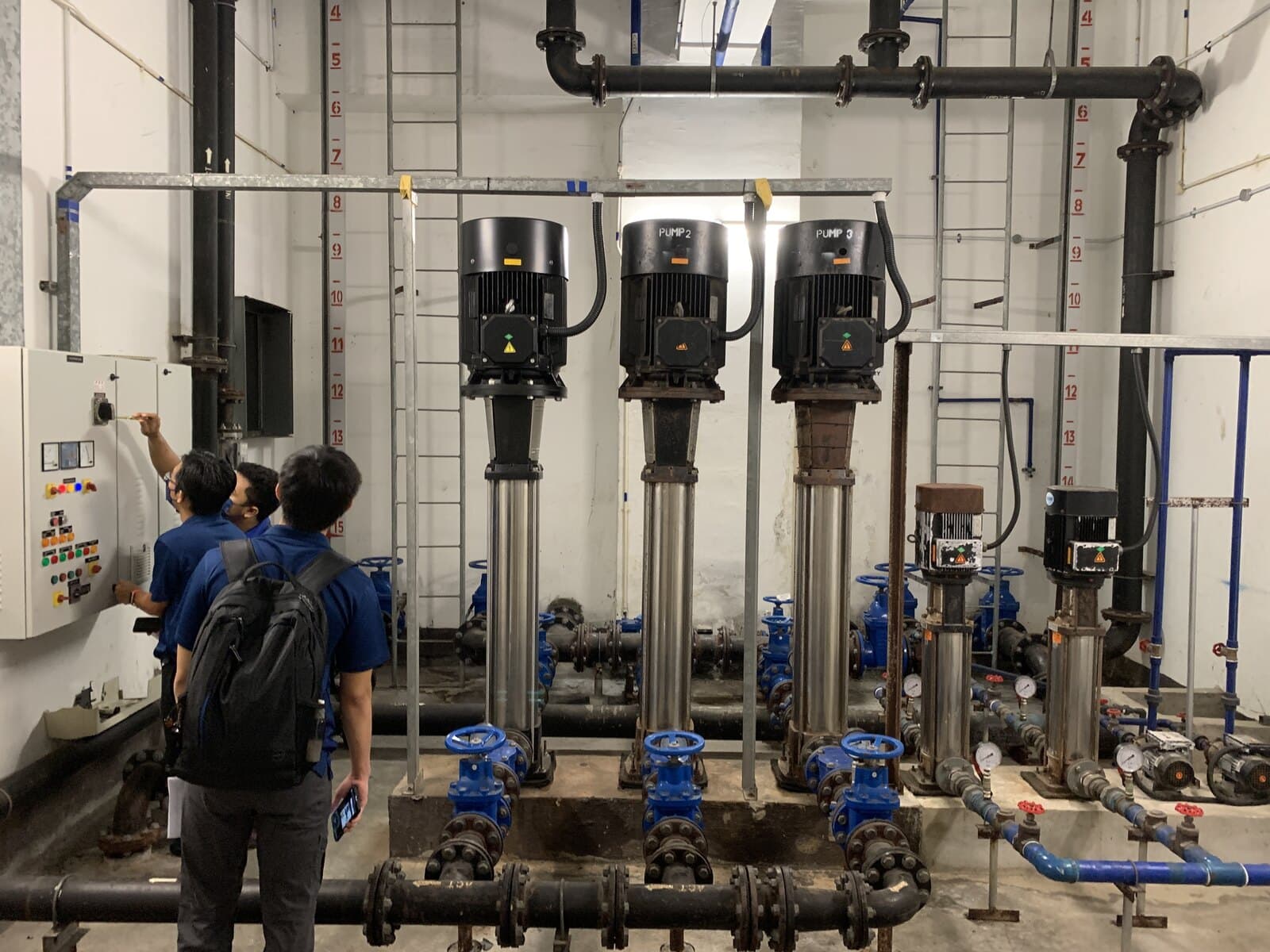Engineers inspecting a pump room control panel during a site survey