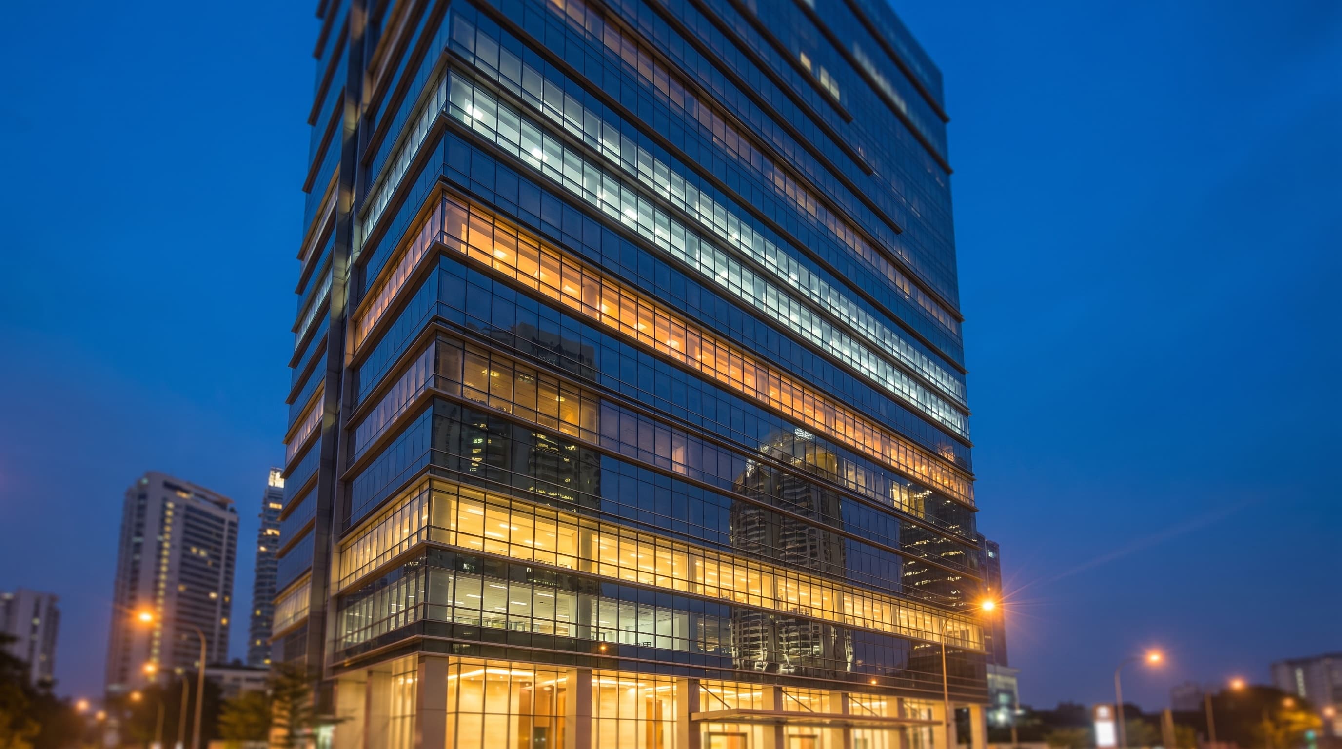 Malaysian office tower glass facade at dusk with tiered bands of lit windows suggesting an energy rating scale