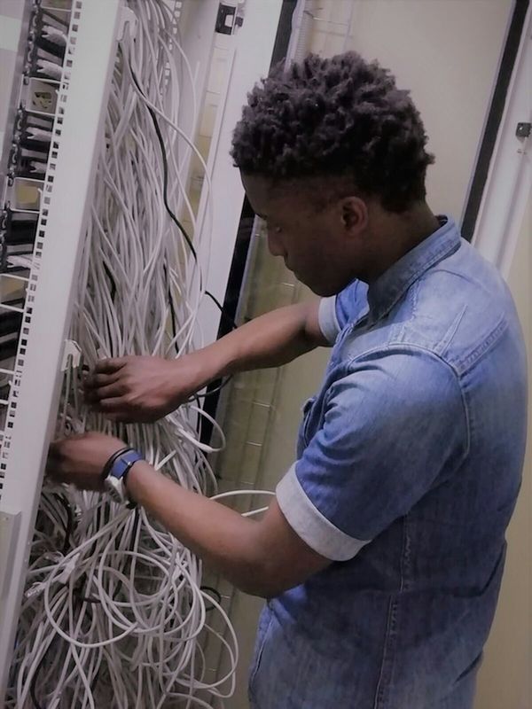 A technician working on network cabling between physical and digital systems