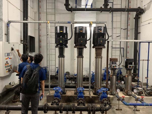 Engineers inspecting a pump room control panel during a site survey
