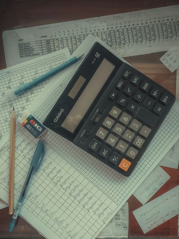 A calculator resting on columns of figures, working through a bill